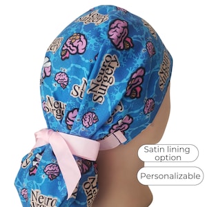 May include: Blue scrub cap with a pink brain pattern and the words "Neuro Surgery". The cap has a pink ribbon tie and the text "Satin lining option" and "Personalizable".