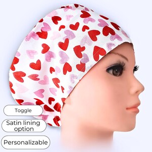 May include: A white surgical cap patterned with red and pink hearts. The cap has a satin lining option and is personalizable. The cap is designed for medical professionals.