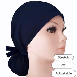 May include: A navy blue head covering with a gathered back and a bow detail. The head covering is shown on a mannequin. The text on the image says "Stretch", "Soft", and "Adjustable".