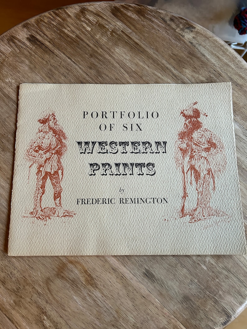 May include: A vintage book cover with a tan background and brown illustrations. The title reads "Portfolio of Six Western Prints by Frederic Remington".