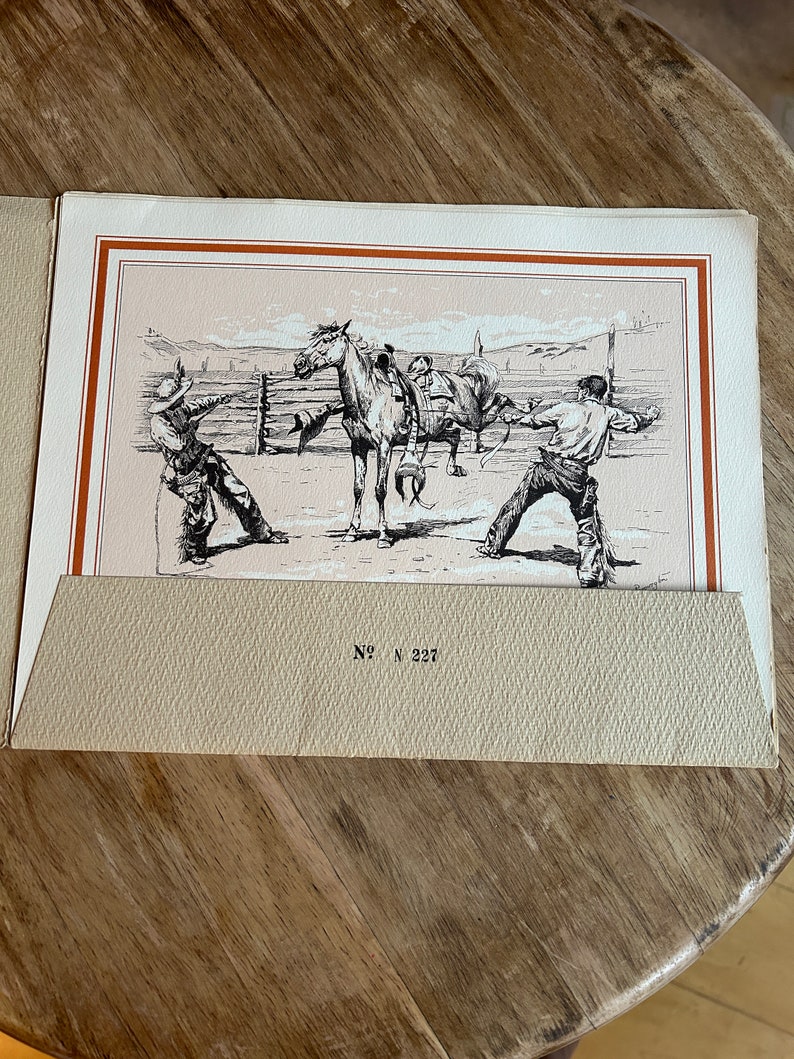 May include: A black and white illustration of two cowboys working with a horse in a corral. The cowboys are wearing hats and boots. The horse is standing in the center of the image. The image is titled "No. N 227".