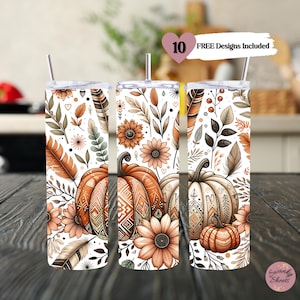 Op de afbeelding: Drie roestvrijstalen bekers met een witte achtergrond en een herfstthema. Het ontwerp bevat pompoenen, bladeren, veren en bloemen in tinten oranje, bruin en crème. De tekst "10 FREE Designs Included" is zichtbaar in de rechterbovenhoek van de afbeelding.