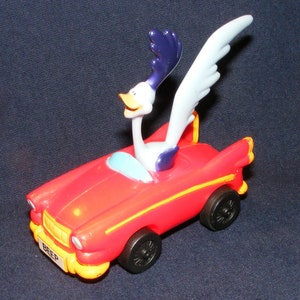 May include: A red toy car with a yellow stripe and the word "Beep" on the front. A cartoon roadrunner with blue and white feathers is driving the car.