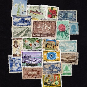 May include: A collection of vintage Lebanese postage stamps featuring diverse illustrations including a fish, flowers, a butterfly, architectural landmarks, a cedar tree, and industrial scenes, with various denominations and Arabic and French text.