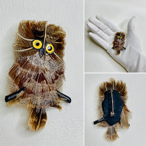 May include: A brown and black owl brooch made of feathers with yellow eyes. The brooch is attached to a black pin.