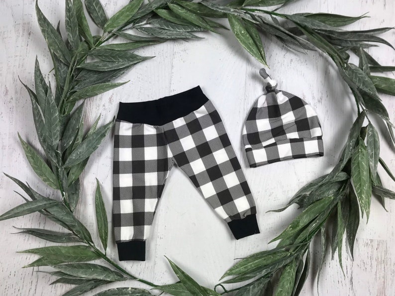 May include: Black and white checked baby leggings and a matching hat. The leggings have a black waistband and the hat has a knotted top.