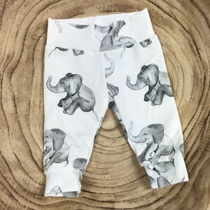 May include: White baby leggings with a gray elephant print. The elephants are in various poses and have a watercolor look.