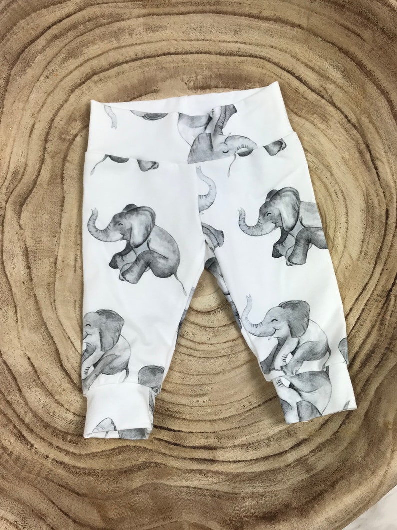 K&ouml;nnte beinhalten: Wei&szlig;e Baby-Leggings mit einem grauen Elefanten-Druck. Die Elefanten sind in verschiedenen Posen und haben einen Aquarell-Look.