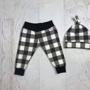 May include: Black and white checked baby leggings and a matching hat. The hat has a knot on top.