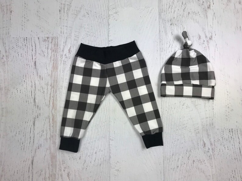 May include: Black and white checked baby leggings and a matching hat. The hat has a knot on top.