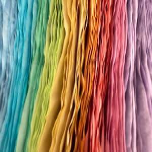 May include: A vertical arrangement of thin, pleated fabric strips in a gradient of colors, transitioning from light blue and turquoise on the left, through lime green, yellow, and orange in the center, to pink and light purple on the right.