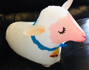 May include: A white and pink inflatable lamb balloon with a blue ribbon and a gold bell. The lamb has a closed eye and a pink nose.