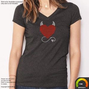May include: Dark gray V-neck t-shirt featuring a red heart design with devil horns and a tail, all made of rhinestones. The shirt's design is centered on the chest. The text "Shirt is for illustration purposes only and is not included" is at the top.