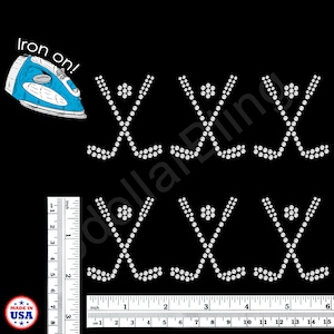 May include: Six iron-on rhinestone hockey stick and puck designs on a black background. A blue iron is in the upper left corner with the text "Iron on!". A ruler shows measurements in inches and centimeters. Made in USA logo.
