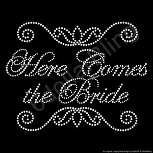 May include: Black background with the phrase "Here Comes the Bride" in white rhinestone lettering. Decorative rhinestone swirls and flourishes are above and below the text, creating a wedding theme.