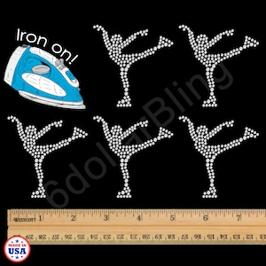 May include: Black background with six white rhinestone ballet dancer iron-on transfers. A blue iron is in the upper left corner with the words "Iron on!". A wooden ruler is at the bottom with the words "Westcott" and "Made in USA".