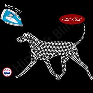 May include: Iron-on rhinestone dog design, 7.25" x 5.2", made in the USA. The dog is depicted in a walking pose, created with white rhinestones on a black background. Includes a blue iron graphic.