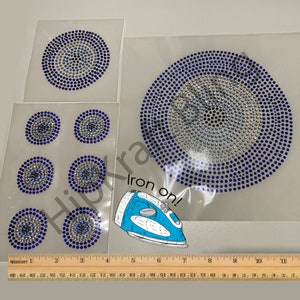 May include: Iron-on rhinestone appliques in a circular design, featuring blue and silver rhinestones. The image includes several appliques of varying sizes, with the text "Iron on!" and a ruler for scale.