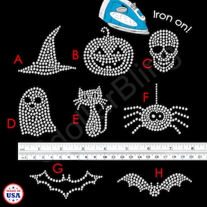 May include: A collection of iron-on rhinestone Halloween designs, including a witch hat, pumpkin, skull, ghost, cat, spider, and two bat shapes. The designs are made of small, sparkling rhinestones on a black background.