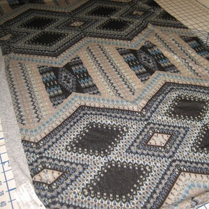 2 Yds. Abstract sweater knit in black, blue, gray, with teal and tan design.