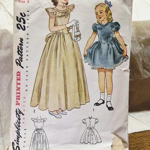 Könnte beinhalten: Ein Vintage-Schnittmusterumschlag von Simplicity, Nummer 2241, Größe 8. Die Vorderseite zeigt Illustrationen von zwei Kleidern: ein langes, blassgelbes Kleid und ein kürzeres, blaues Kleid mit Puffärmeln. Text beinhaltet Simplicity, 2241 und 25c.