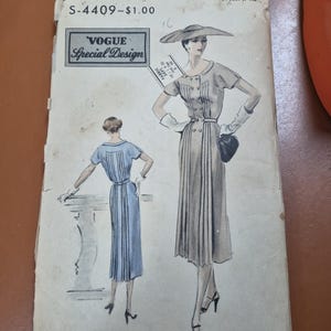 Pode incluir: Padrão de costura Vogue Special Design vintage, S-4409, com ilustrações de um vestido com saia plissada e detalhes de botões. O padrão é tamanho 16, com 86 cm de busto e 94 cm de anca. Copyright 1956.