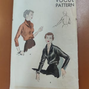 Könnte beinhalten: Vintage Vogue Schnittmuster für eine Bluse, Größe 14, Brustumfang 81 cm. Das Schnittmuster zeigt zwei Illustrationen von Frauen, die die Bluse tragen, eine in Braun und eine in Schwarz.
