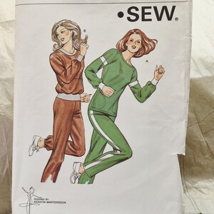 May include: A Kwik Sew pattern envelope 1069 for sizes XS, S, M, and L. The illustration shows two tracksuits: one brown with a V-neck and one green with a crew neck, white sleeve stripes, and white side leg stripes. The text includes Kwik Sew, Pattern 1069, and Kerstin Martensson.