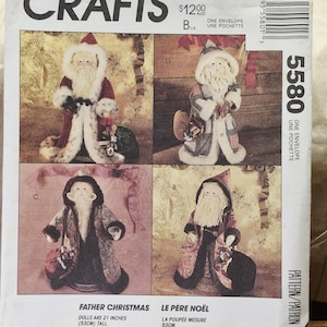 Op de afbeelding: Een McCall's Crafts naaipatroon-envelop 5580 voor Kerstman-poppen. De voorzijde toont vier variaties van figuren met lange baarden, gekleed in gewaden en mutsen. De tekst bevat 'McCall's Crafts', '5580' en 'La poupée mesure 53cm'.