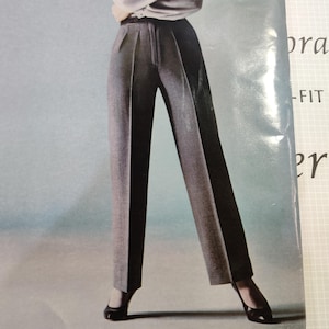 Può includere: Un paio di pantaloni grigi a vita alta, plissettati, con una cerniera centrale e una chiusura a bottone. I pantaloni sono sartoriali e hanno una gamba dritta.
