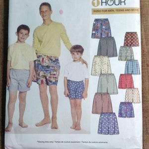 以下が含まれることがあります： 「1 HOUR SIZED FOR MEN, TEENS AND BOYS」と記されたボクサーパンツの型紙封筒。表紙には、様々な柄のボクサーパンツとTシャツを着用した3人の人物と、12種類の生地デザインのイラストが掲載されています。