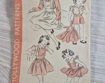 Op de afbeelding: Vintage Hollywood Patterns naaipatroon voor meisjesjurken. De omslag toont illustraties van kinderkleding in verschillende stijlen. Het patroon is voor 8-jarigen en kost 15 cent.