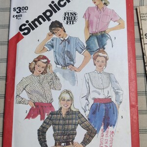 Könnte beinhalten: Simplicity Schnittmuster 5663, Größe 8 Miss. Das Cover zeigt Illustrationen von Damenblusen und -hemden in verschiedenen Stilen. Das Cover hat einen roten Rand und die Worte "Fuss Free Fit".