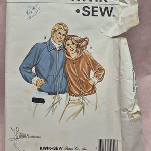 May include: Vintage Kwik Sew pattern 938 featuring illustrations of a blue jacket and a brown hooded jacket. The pattern includes chest sizes 32-44 inches. Designed by Kerstin Martensson. Kwik Sew Pattern Co., Inc.