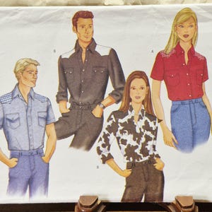 May include: A sewing pattern envelope featuring illustrations of four individuals wearing button-down shirts with western-style yokes. The designs include a short-sleeved light blue shirt, a long-sleeved black shirt, a cow-print shirt, and a red shirt.