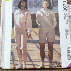 May include: A sewing pattern for a two-piece outfit. The pattern is for a size medium (14-16). The pattern includes a long-sleeved top with a contrasting color panel and a pair of pants. The pattern is called "Learn to Sew for Fun".