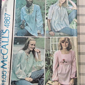 May include: A vintage sewing pattern for a set of tops. The pattern includes four different styles, with options for long or short sleeves. The pattern is for misses' sizes and includes extra cut lines for maternity fit. The pattern is from McCall's and is number 4867.