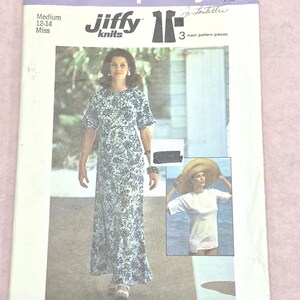 Puede incluir: Un sobre de patrón de costura Simplicity 6922 Jiffy knits para un vestido de talla mediana 12-14 miss. El frente muestra un vestido largo con estampado floral azul y blanco y una camiseta blanca. El texto incluye 6922, Simplicity, Jiffy knits y Sized for stretch knits only.