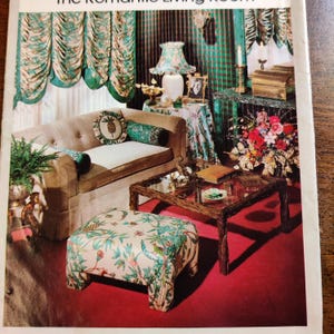 May include: A retro living room interior with a beige sofa, patterned cushions, and a glass-topped coffee table. The room features floral curtains, a patterned footstool, and a lamp with a matching shade. The colour scheme includes beige, green, and red.