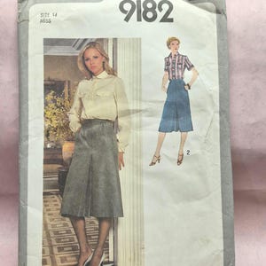 May include: Vintage Simplicity sewing pattern 9182, size 14 Miss. The pattern features illustrations of a woman wearing a blouse and skirt. The pattern's cover is off-white with the text "Simplicity" and "The Newest Fashions To Sew".
