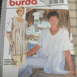 May include: A sewing pattern cover featuring illustrations of a blouse and vest. The blouse is white with short sleeves and buttons. The vest has a floral pattern. The text "BLOUSE, VEST" is visible.