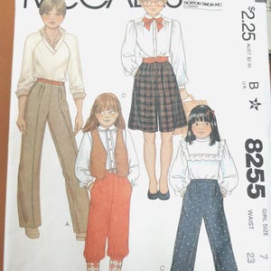以下が含まれることがあります： ウエスト58cmの女の子用サイズ7のMcCall's型紙封筒8255。イラストには、白いブラウスとベージュのズボン、チェック柄のスカート、オレンジ色のニッカボッカ、青い柄のズボンなど、4種類の服装が描かれています。