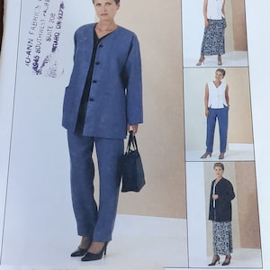 May include: A blue pantsuit with a matching jacket and pants. The jacket has a collar, long sleeves, and a button closure. The pants have a straight leg and a relaxed fit. The model is wearing black heels and carrying a black handbag.