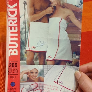 Pode incluir: Um padrão de costura vintage para um par de roupões brancos com guarnições vermelhas. O padrão é para o padrão Butterick número 206 e custa $ 2,50. O padrão inclui instruções para fazer os roupões e os chinelos.