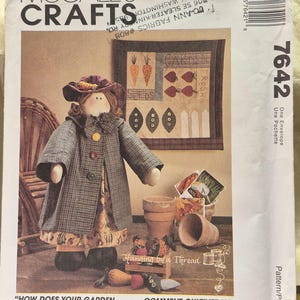 May include: McCall's Crafts 7642 sewing pattern envelope featuring a doll in a plaid coat and hat, a small garden quilt, and fabric vegetables. The text includes 'How Does Your Garden Grow?' and notes the doll is 18.5 inches tall and quilt is 14 by 14 inches.