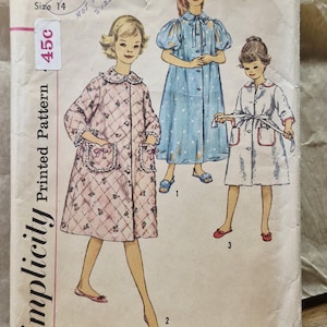 May include: A vintage Simplicity sewing pattern envelope, number 3244, for a girl's size 14 robe. The front features illustrations of three different robe styles, including a quilted pink floral design, a blue polka dot robe, and a white robe.