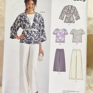 May include: A New Look sewing pattern envelope S0183 featuring illustrations of a wrap jacket with a floral print, a short-sleeved top, and wide-leg trousers. The front shows a model wearing the jacket and trousers with a white shirt and a belt.