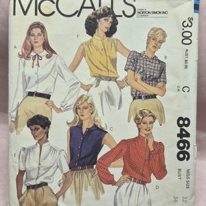 May include: Vintage McCall's sewing pattern featuring illustrations of blouses. The pattern cover displays various blouse styles, including a white blouse with a bow, a yellow sleeveless top, and a red polka-dot blouse. The pattern number is 8466.
