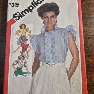 May include: Simplicity sewing pattern envelope, size 8 Miss. The cover features a woman wearing a blue and white striped blouse with ruffles and a white skirt. The envelope has the number 5818 and the price $3.00.