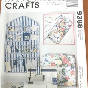 Może przedstawiać: Wzór krawiecki McCall's Crafts z maszyną do szycia, paskowym organizerem ściennym i akcesoriami z tkaniny kwiatowej. Wzór zawiera osłonę maszyny do szycia i małą kwiatową torebkę. Numer wzoru to 9388.